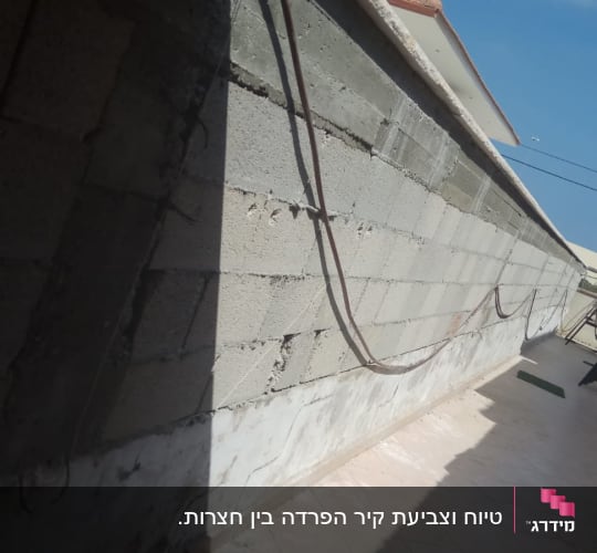 קיר חוץ מבלוקים חשופים בחצר בית לפני עבודות טיח וצביעה